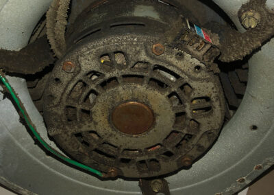 A close-up of a dust-covered motor in an HVAC system, with visible grime and wear.