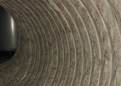 Close-up of a dusty, discolored air duct interior with visible dirt buildup along the flexible lining.