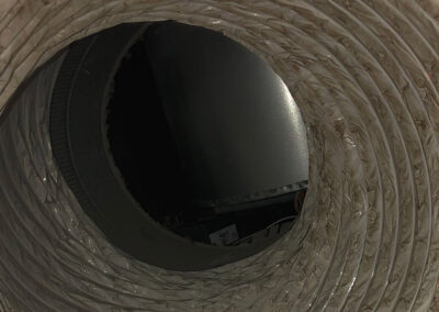 Close-up of a dirty air duct showing accumulated dust and grime on the inner surface, with visible discoloration and buildup in the spiral ridges.