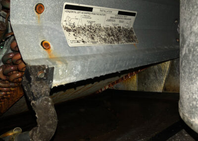 A dusty, rusted air conditioning evaporator coil with heavy moisture build-up and visible signs of rust and grime.