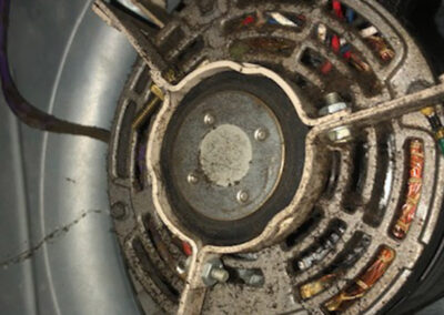 A dirty and rusted motor fan in an HVAC system, with dust buildup visible on the components.