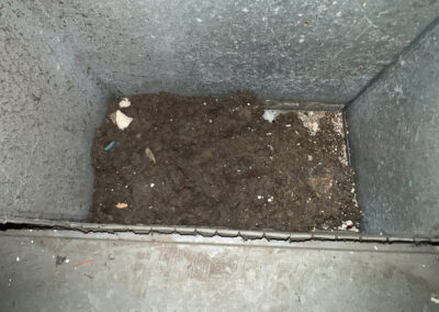 A large pile of dirt and debris collected at the bottom of a vent.