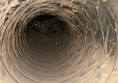 Close-up view of a metal duct filled with thick layers of dust, dirt, and debris, almost blocking the airflow.