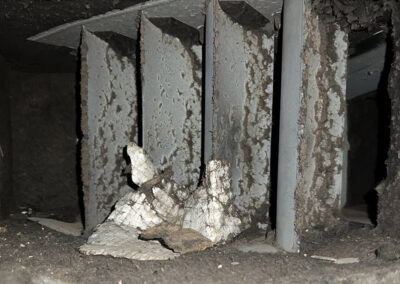 Heavily dust-filled ventilation duct, showing layers of debris and particles coating the walls of the ductwork.