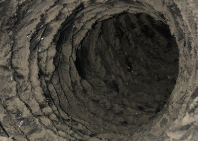 Extremely dirty and dust-covered air duct, with thick layers of dust clinging to the inner walls, blocking airflow.