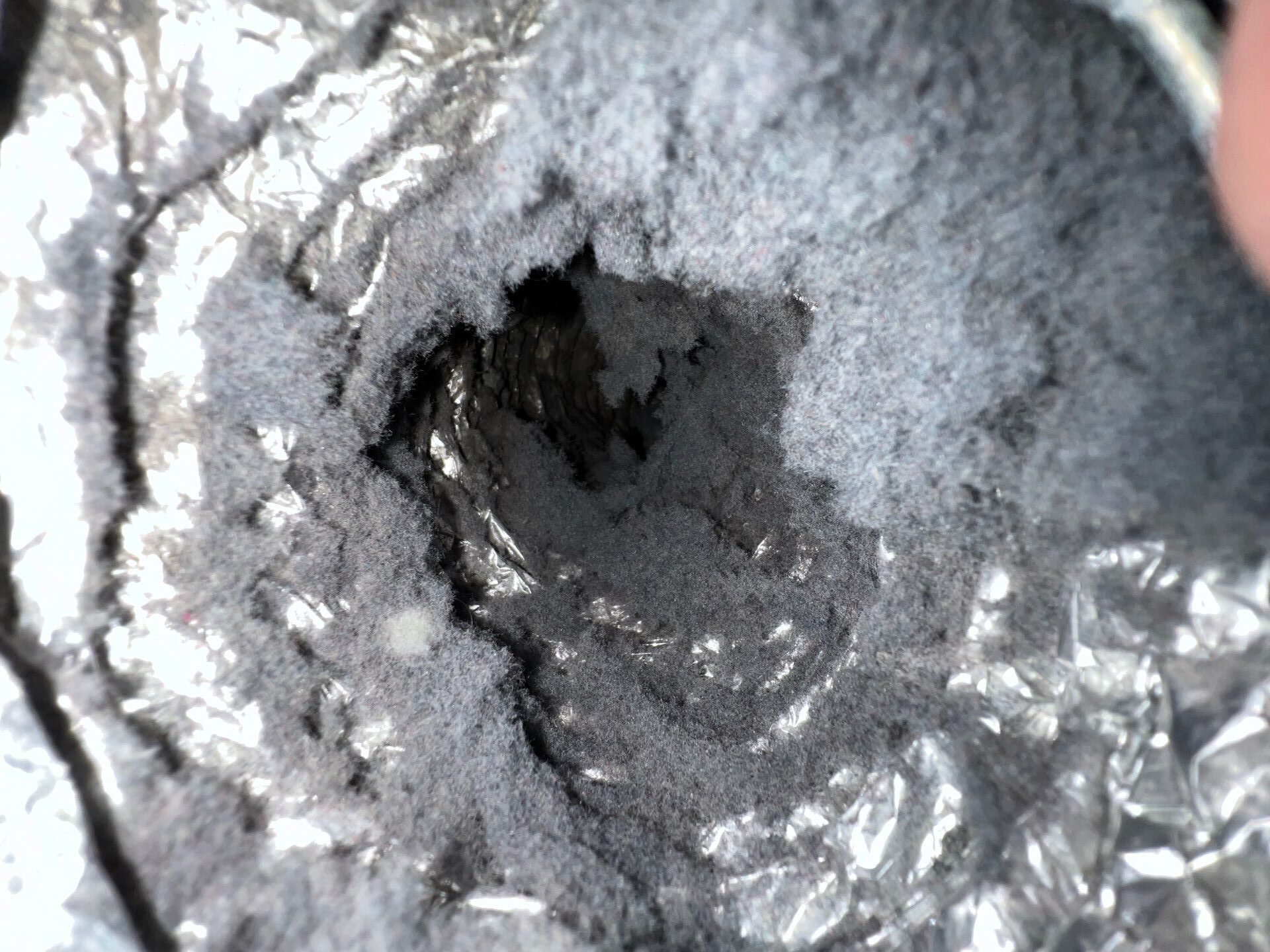 A dusty and dirty air vent filled with thick layers of dust, dirt, and debris surrounding the opening and grille.